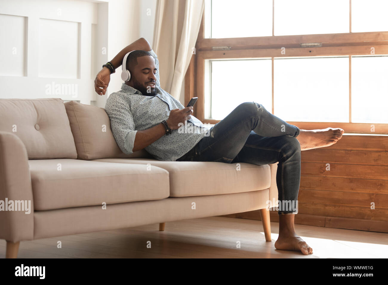 Hombre Negro relajante en el sofá en casa, escuchar música Fotografía de  stock - Alamy