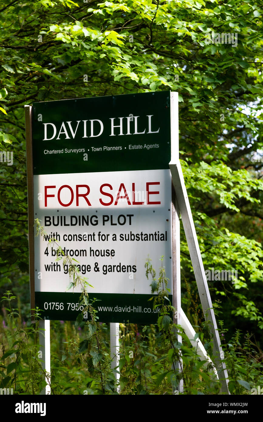 A la venta un cartel en la venta de una parcela de tierra con el permiso de planificación para la construcción de una casa. Foto de stock