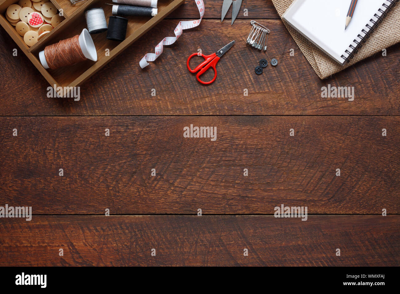 Imagen aérea laicos plana del diseñador de moda artículos concepto de fondo.La vista superior o adaptar accesorios de costura en equipos modernos rústicos de madera marrón en casa Foto de stock