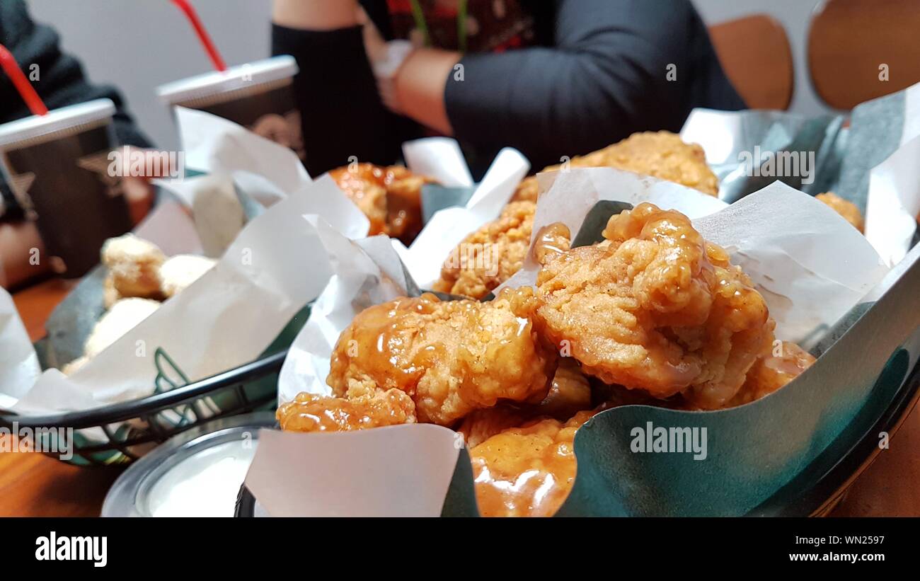 Close-up de pollo frito contra la Mujer sentada en un restaurante Foto de stock