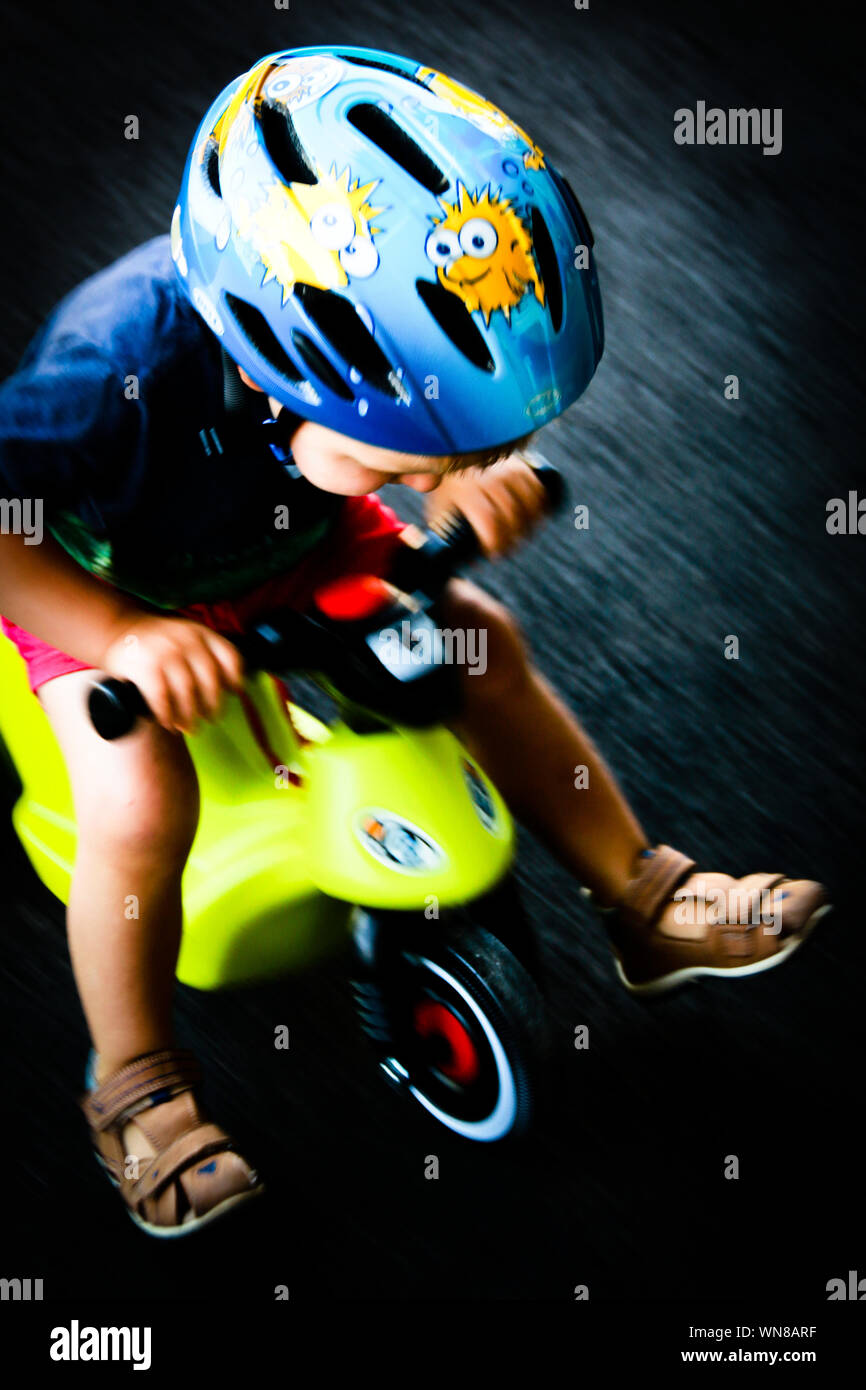 Niño de 2 años conduciendo su moto de juguete con gran velocidad a través  de su patio de recreo Fotografía de stock - Alamy
