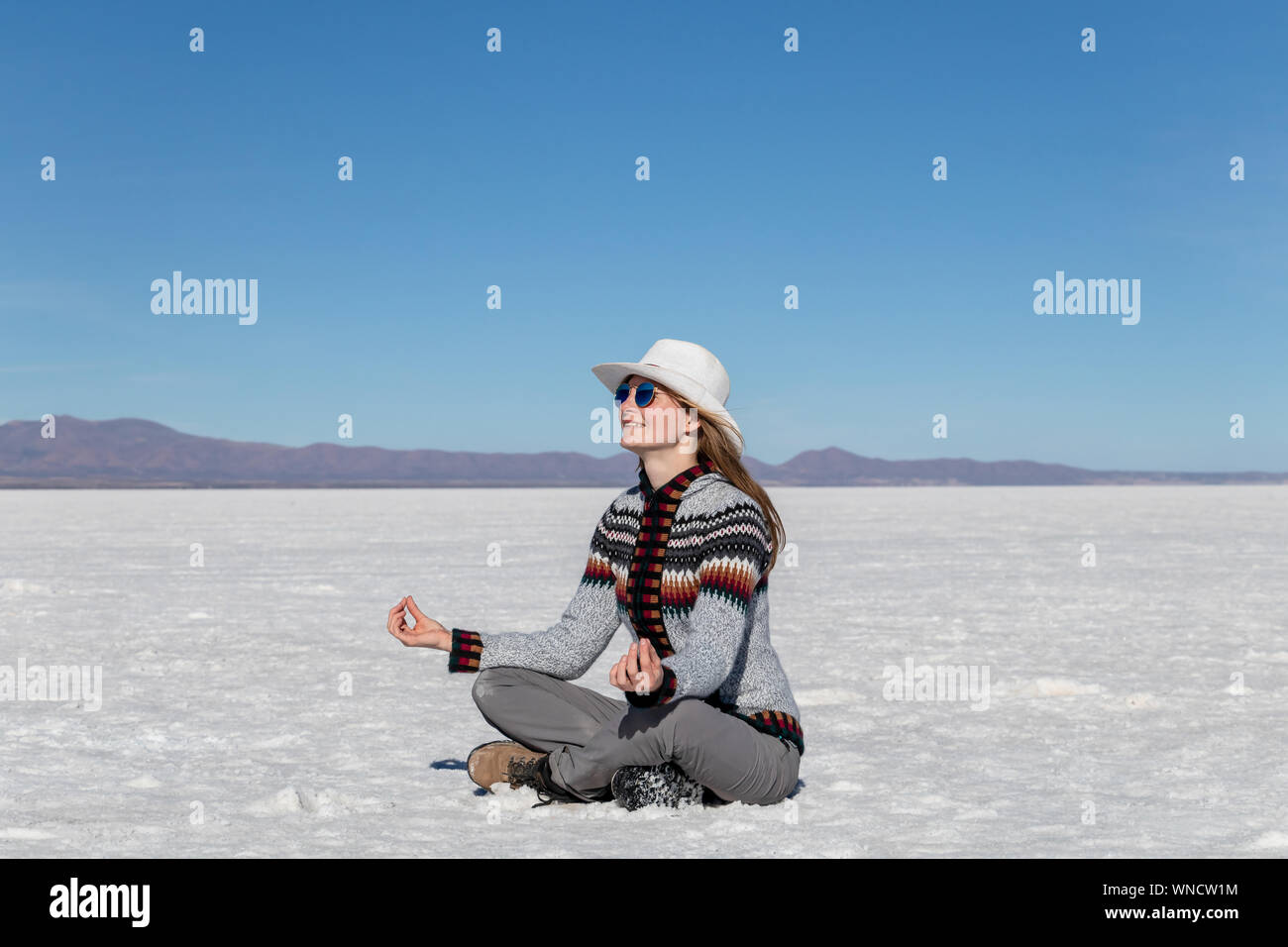 Alegre chica rubia positivo ropa casual sentado en el salar de Uyuni  desierto, meditando en el yoga pose. Modelo casual caucásica vistiendo  sombrero y Fotografía de stock - Alamy