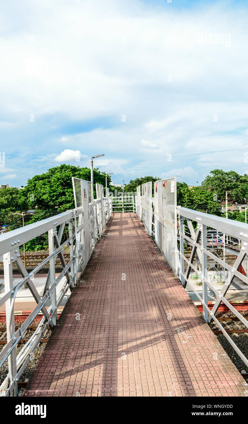 Pie sobre el puente de ferrocarril o simplemente llama a través de un puente en una estación de ferrocarril casi completa de la plataforma para que los pasajeros puedan pasar a través de una estación de tren p Foto de stock