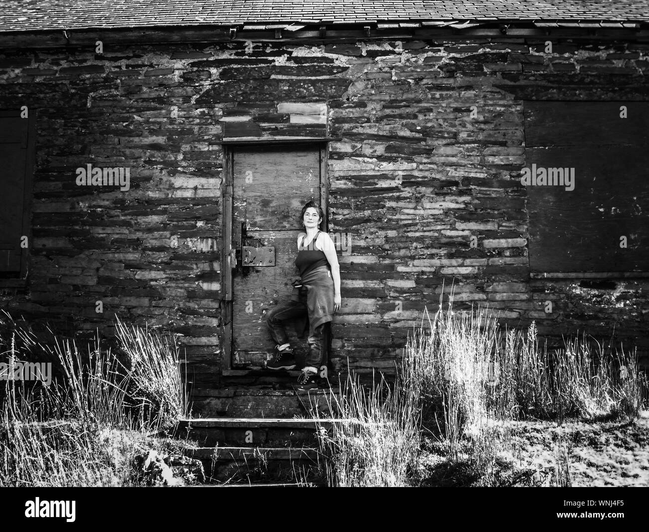 Retrato de mujer adulta medio pie fuera vieja casa abandonada Foto de stock