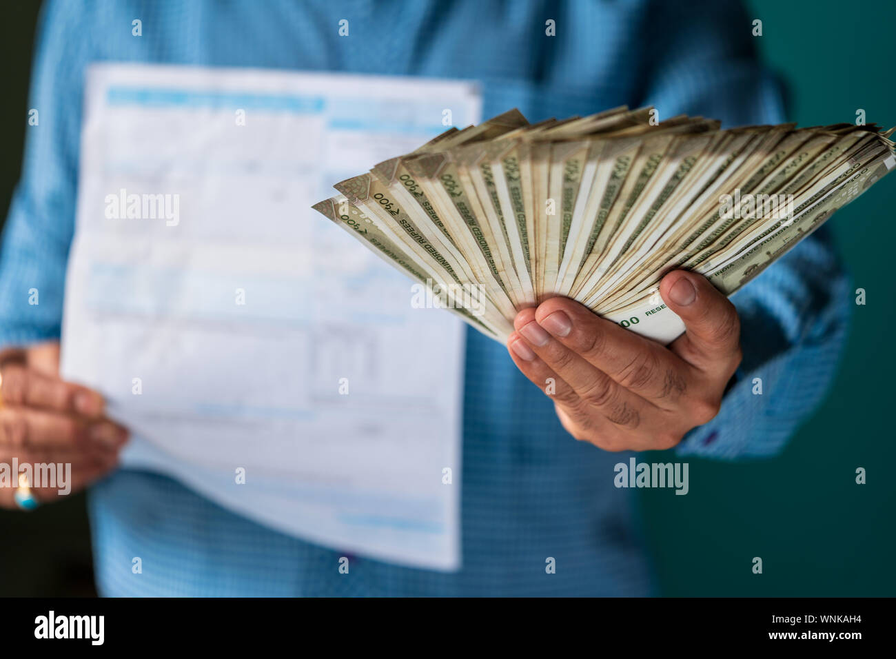 Ciudadano varón indio pagando sus comestibles, electricidad, agua, gas, DTH y otras facturas mensuales y los impuestos. Concepto de pago de impuestos y con copyspace. Foto de stock