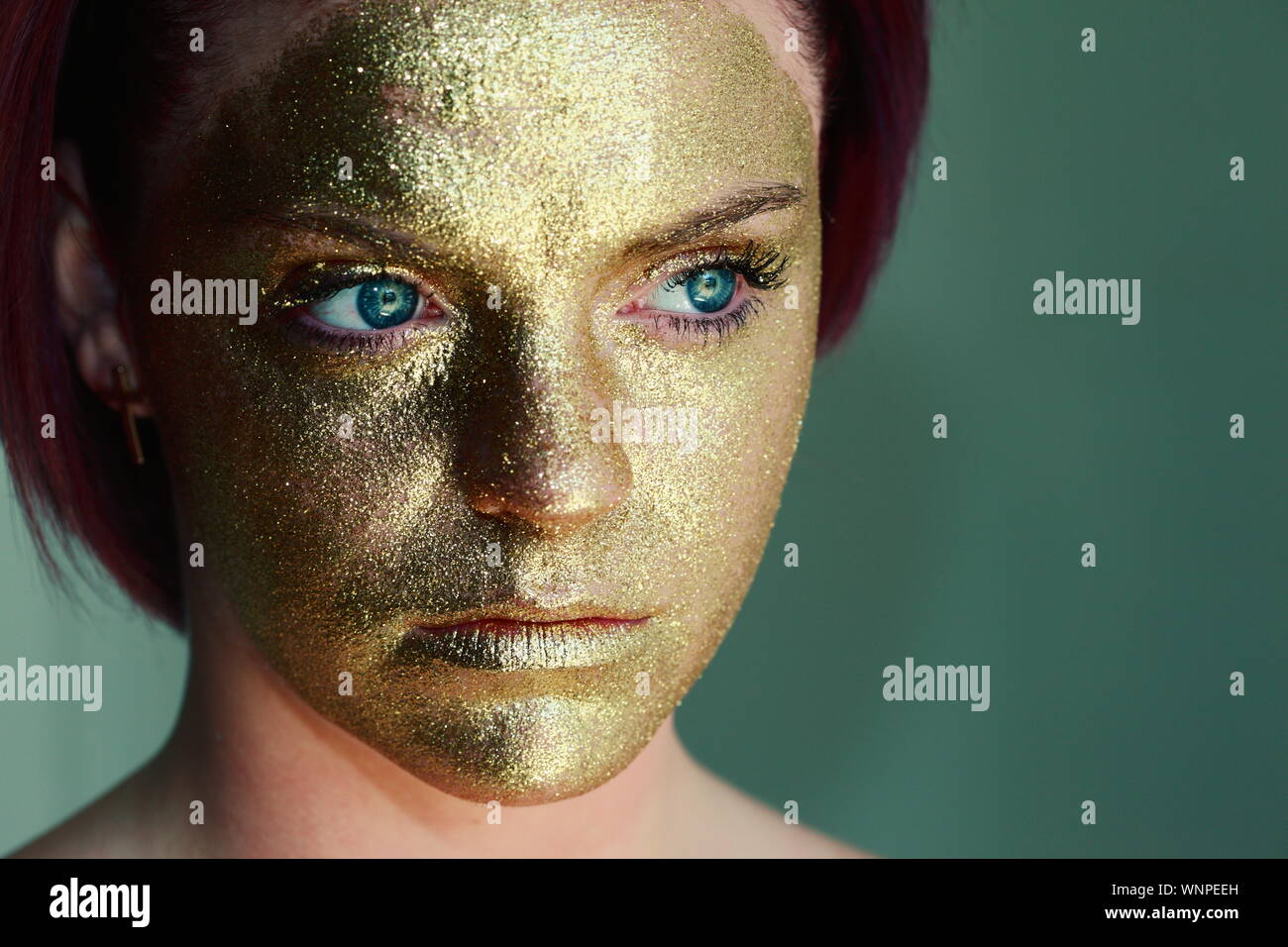 Close-up de Mujer Cara con pintura dorada contra el fondo verde Fotografía  de stock - Alamy