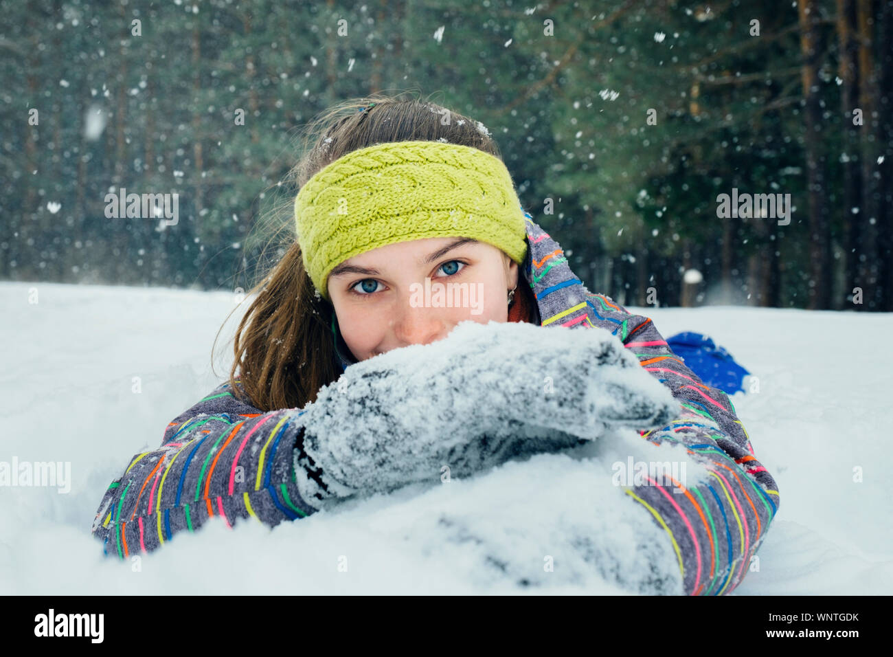 La niña se encuentra en la nieve y sonrisas Foto de stock