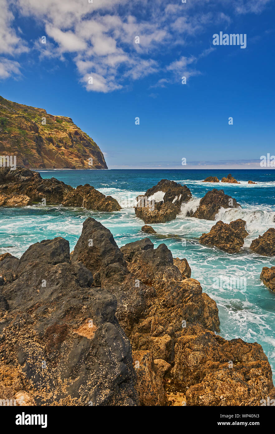 Océano Atlántico y escarpado litoral volcánico del norte de Madeira en Porto Moniz, con olas rompiendo sobre las rocas y la costa. Foto de stock