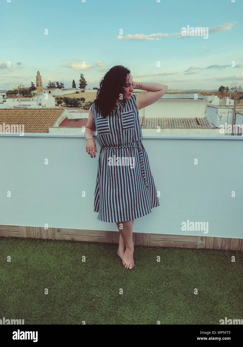 Mujer relajado en un traje a rayas y descalzo sobre el césped de la terraza Foto de stock