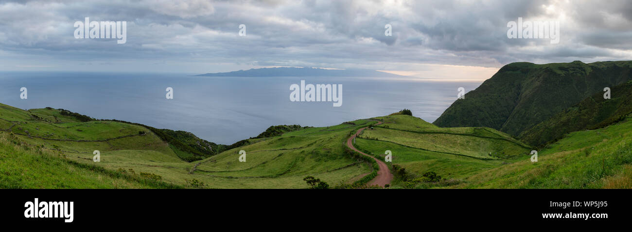 Pintoresco paisaje montañoso panoram de la costa sur de la isla de Sao Jorge, con vistas sobre la isla de Pico con la Ponta do Pico Mountain en las nubes, Foto de stock