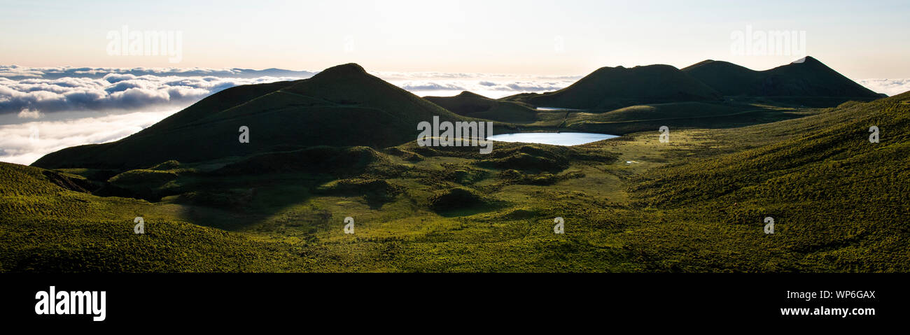 Panorama impresionante paisaje por encima de la isla de Pico cloudline mostrando Lago de Peixinho (Lagoa do Peixinho), verdes prados con viejo volcán conos y c Foto de stock