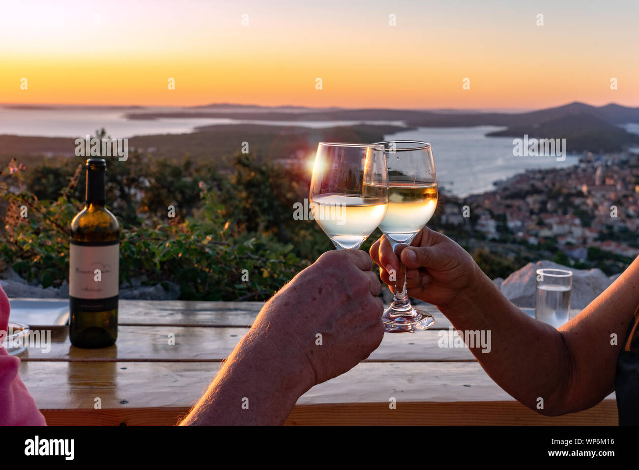 Hacer un brindis con vino a través de una vista panorámica de las islas losinj croata en el golfo de Kvarner al atardecer Foto de stock
