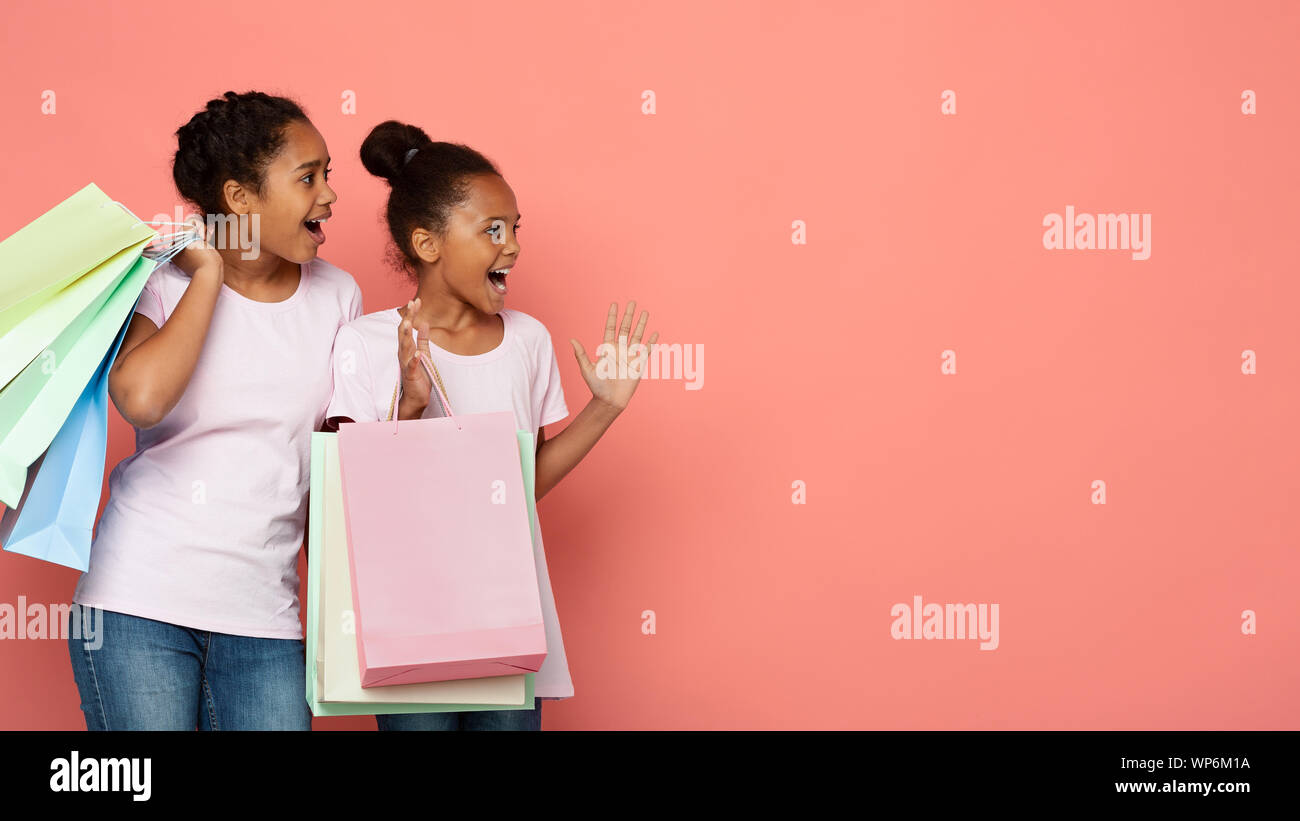 Las niñas africanas entusiasmados con bolsas de compras en busca de lado Foto de stock