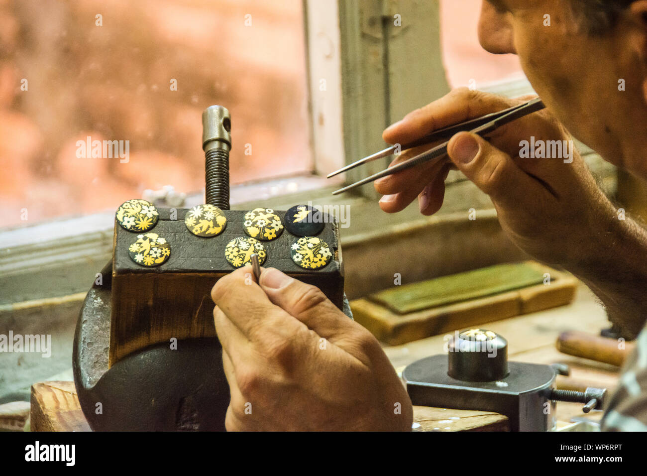 Un artesano español trabaja en pequeñas piezas de arte lo suficientemente pequeñas como para requerir el uso de un par de pinzas. Foto de stock