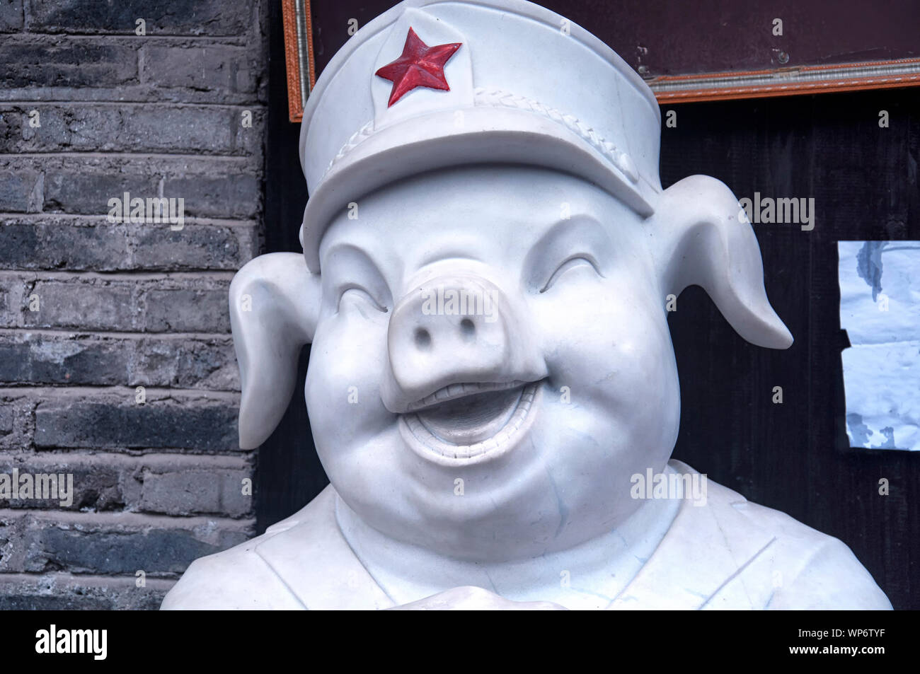 Una estatua de mármol feliz cerdo vistiendo un ejército chino sombrero en Fenghuang antigua ciudad, provincia de Hunan, China. Foto de stock