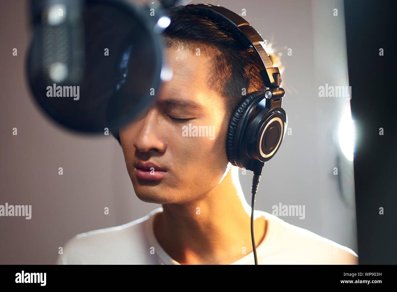 Joven músico asiático cantante cantando la canción en estudio de grabación Foto de stock