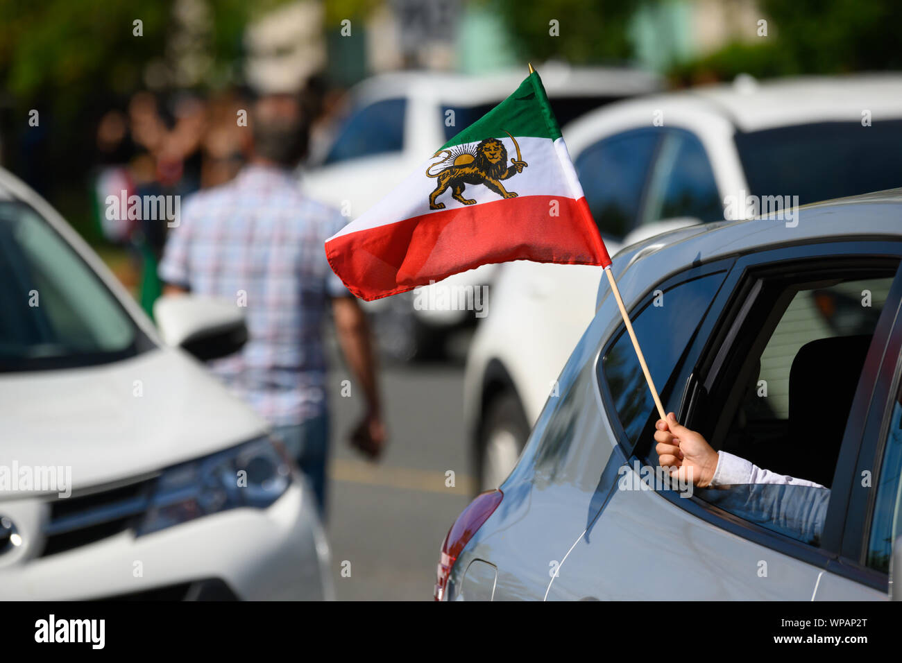 Un niño ondas orgullosamente el león y sol iraní ('Shir o Khorshid') bandera desde un automóvil en la parte superior de la ventana en Yonge desfile persa. Foto de stock