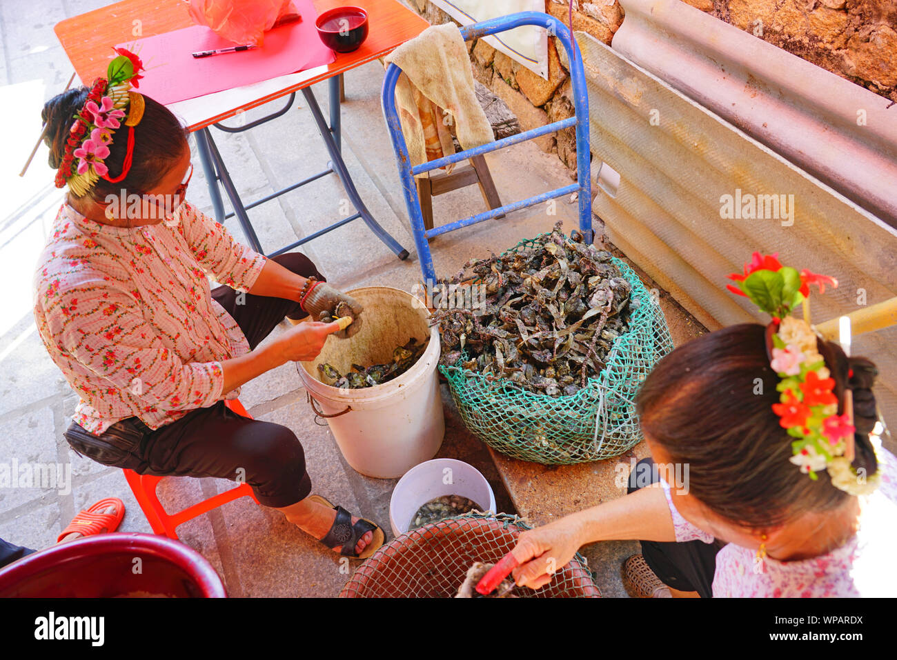 QUANZHOU, CHINA - 15 Jun 2019- Vista de Mazu pescadoras en el colorido cultural tradicional de peinado y traje shucking ostras en la shell en Villa Xunpu Foto de stock
