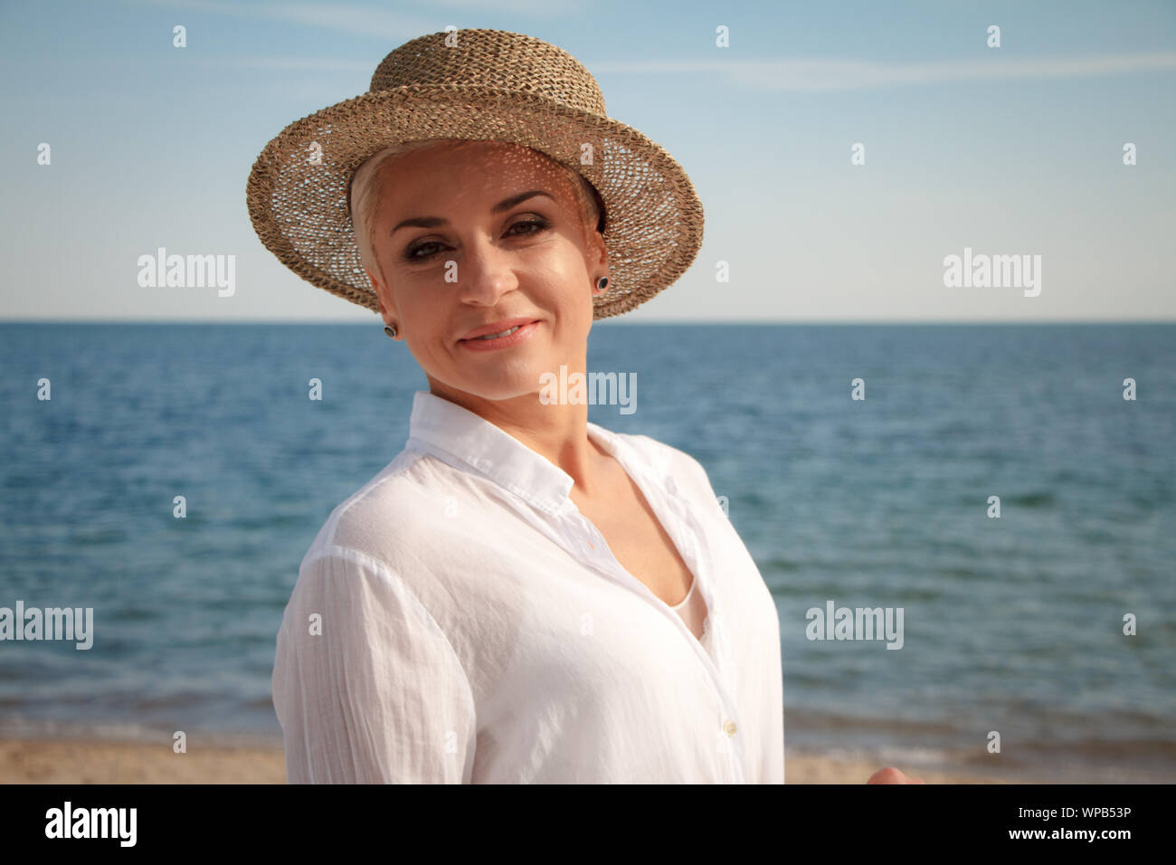 Encantador Joven Con Un Corte De Pelo Corto En Un Sombrero De Playa En La Playa Riendo Y Mirando Al Mar El Concepto De Unas Vacaciones De Verano Fotografia De Stock