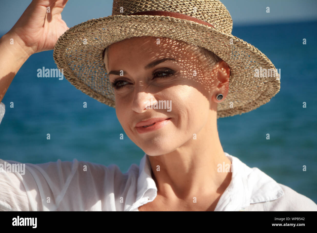 Encantador Joven Con Un Corte De Pelo Corto En Un Sombrero De Playa En La Playa Riendo Y Mirando Al Mar El Concepto De Unas Vacaciones De Verano Fotografia De Stock