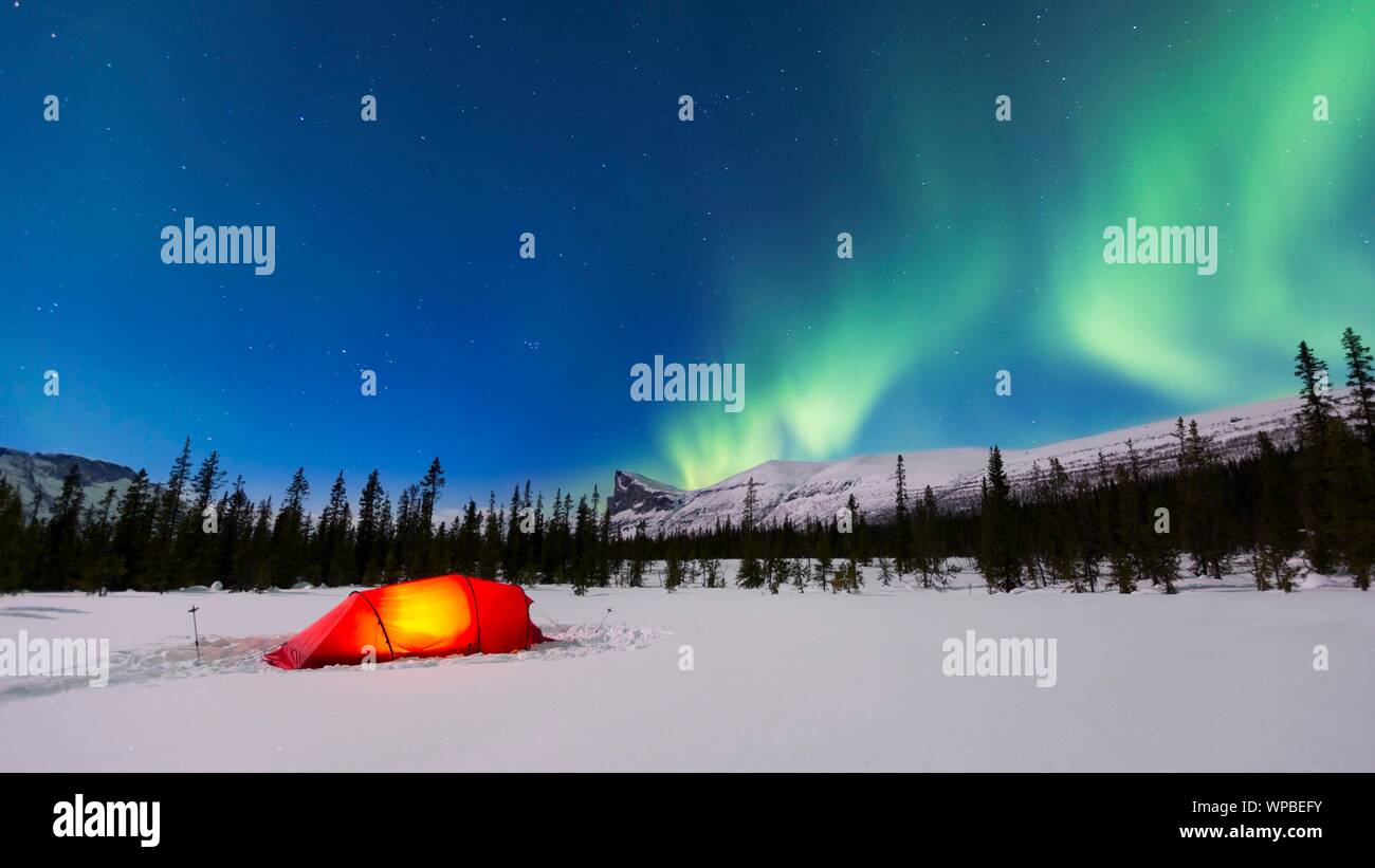 Las Luces del Norte (Aurora Borealis) encima de una carpa roja iluminada en invierno, Kungsleden, en la Provincia de Laponia, Suecia Foto de stock