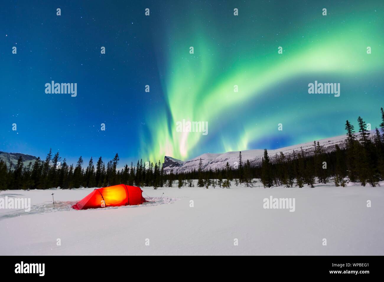 Las Luces del Norte (Aurora Borealis) encima de una carpa roja iluminada en invierno, Kungsleden, en la Provincia de Laponia, Suecia Foto de stock