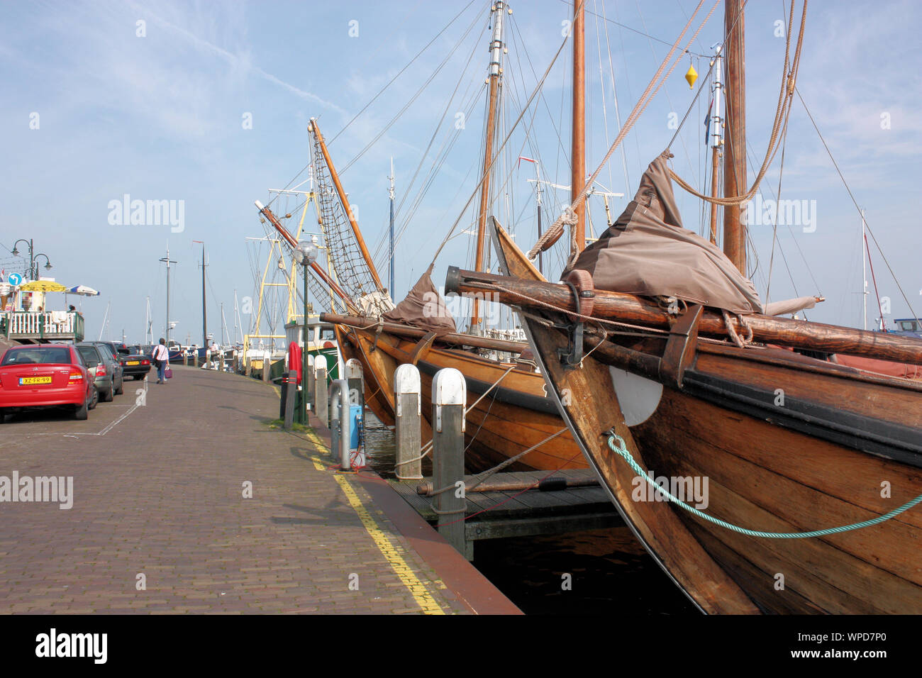 Una animada calle residencial y de tiendas en Volendam, donde se puede ver edificios tradicionales de madera en un lado y los barcos de pesca en el otro lado. Foto de stock