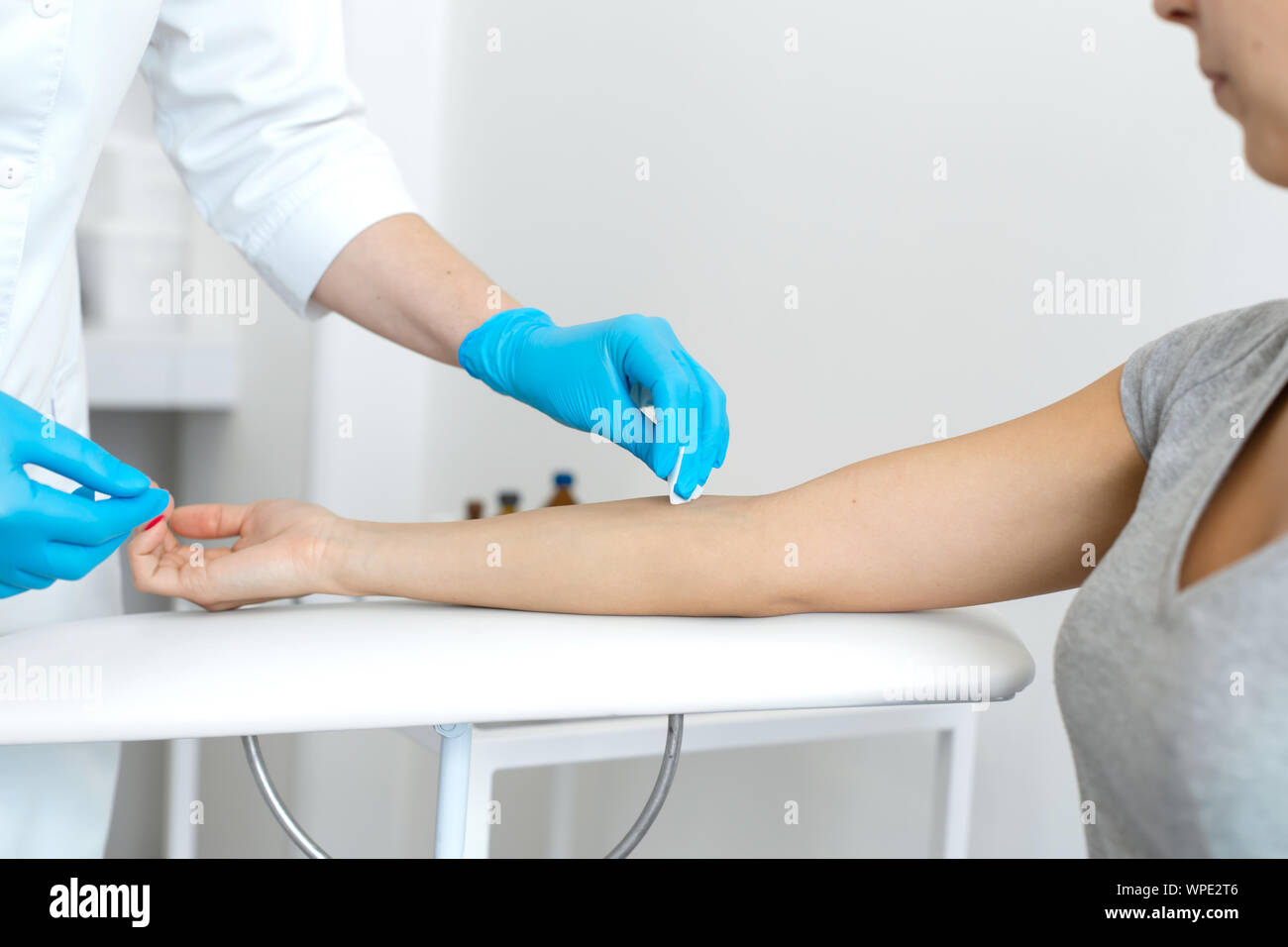 La enfermera roza la mano con alcohol antes de tomar sangre de una vena,  usualmente para pruebas. Desinfecta el lugar de introducción de una aguja  con un antiséptico Fotografía de stock -