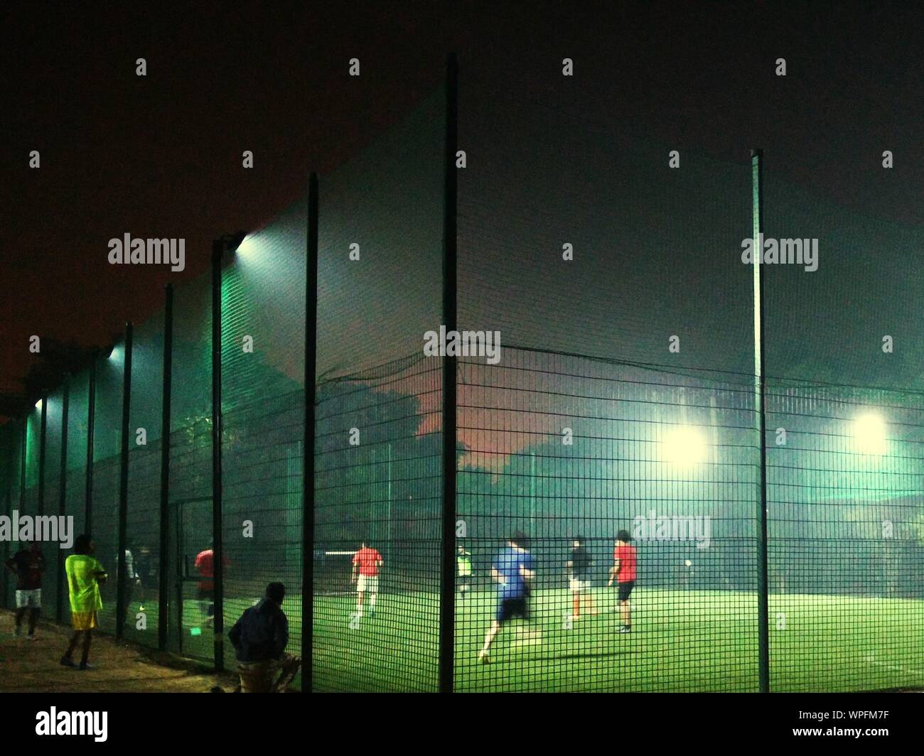 Los hombres jugando al fútbol en el patio de recreo de la noche