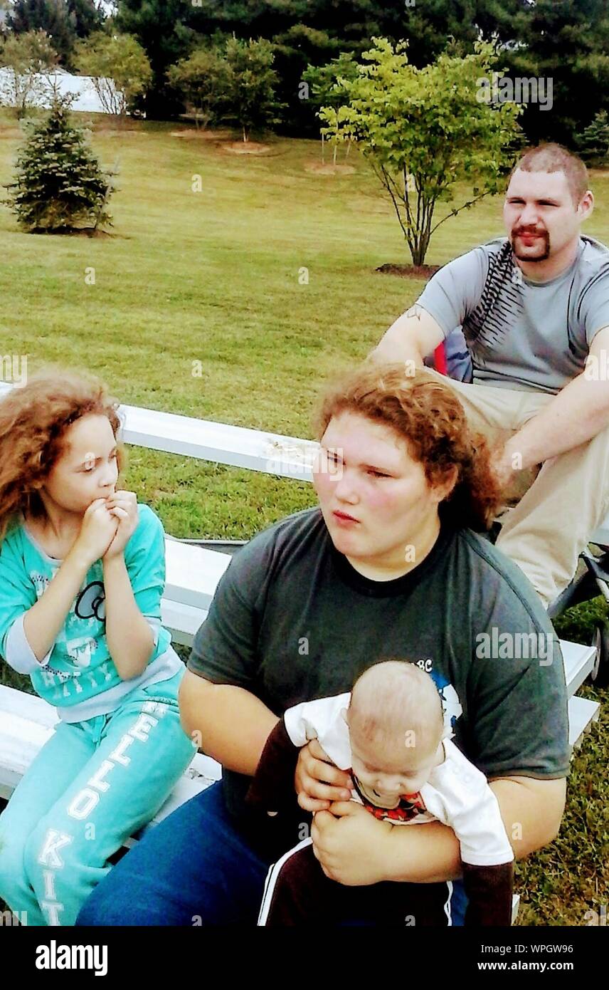 Un alto ángulo de vista de familia con dos niños sentados en la mesa de picnic al parque Foto de stock