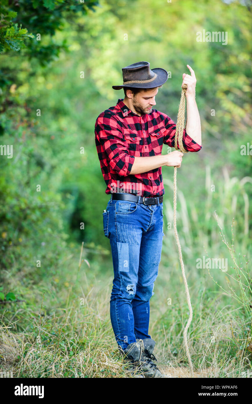 Cowboy en campo. Hombre vestido con sombrero mantenga la cuerda. Rancho  ocupaciones. La herramienta Lazo. Cowboy americano. Lasso atado envuelto.  La vida occidental. Vaquero hombre naturaleza de fondo. Propietario del  rancho. attle