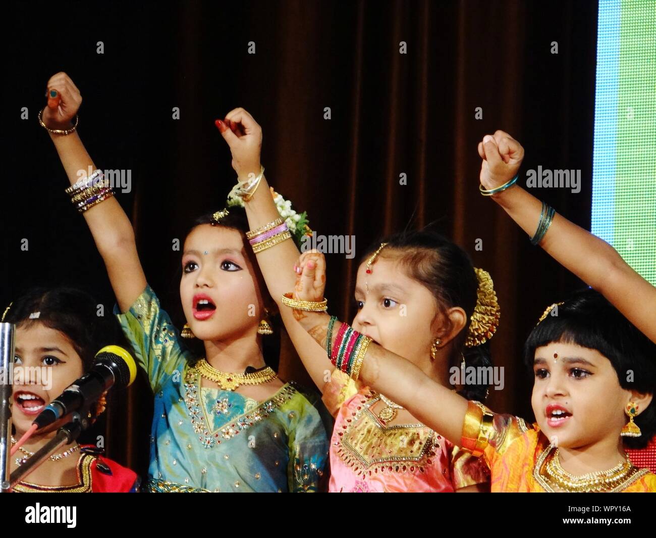 Cute Girls vistiendo ropas tradicionales y maquillaje mientras canta en el escenario Foto de stock
