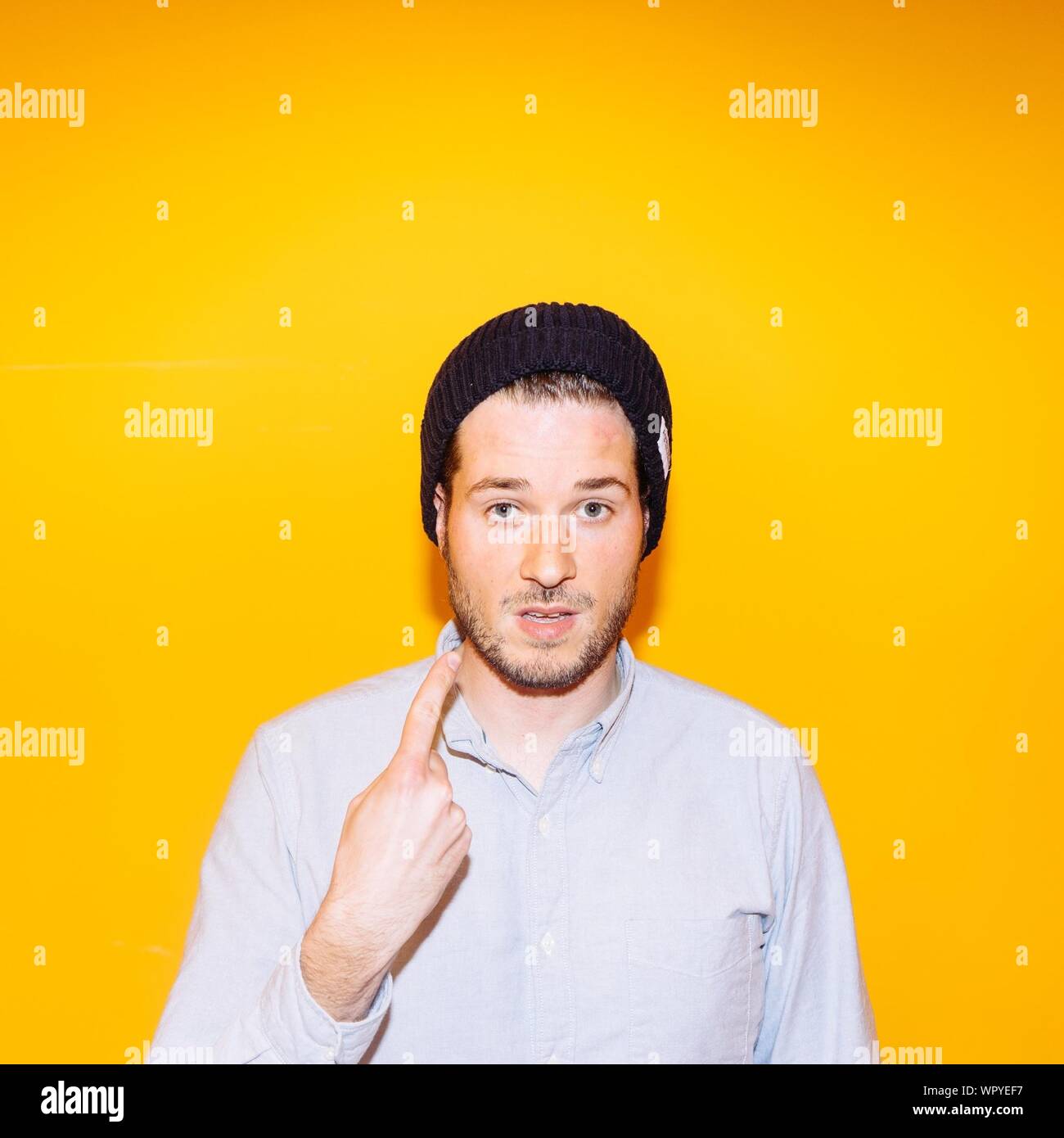 Retrato de Joven mostrando el dedo índice contra el fondo amarillo Foto de stock