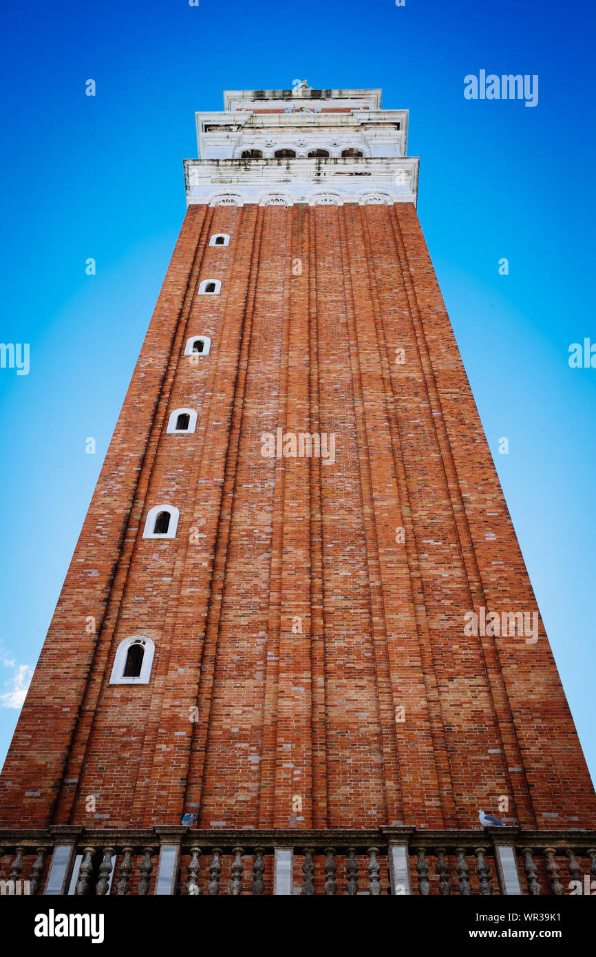 Ángulo de visión baja del campanario de la plaza San Marco contra el cielo azul claro Foto de stock