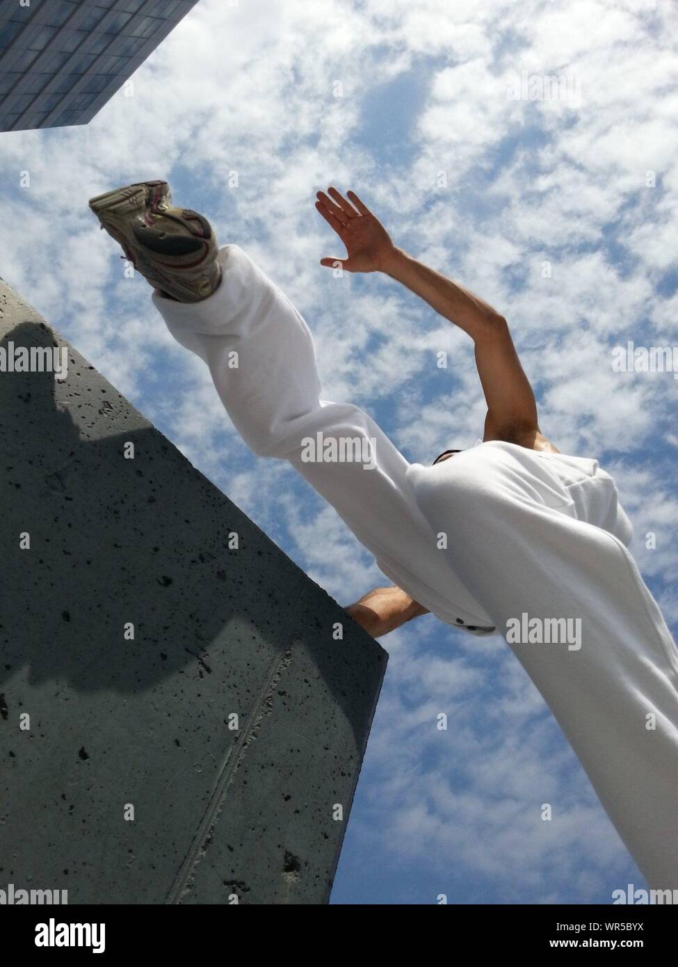 Hombre saltando entre el zócalo de hormigón visto desde abajo Foto de stock