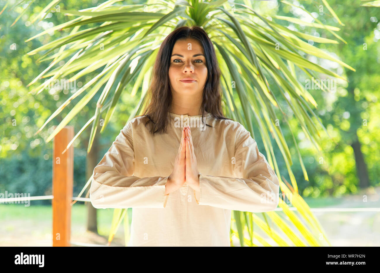 Mujer morena medita sobre la naturaleza de fondo. Ejercicios de yoga en el retiro. Foto de stock