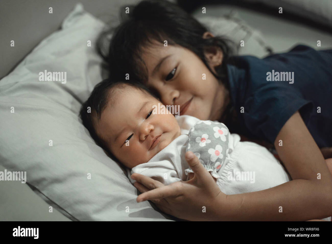 Hermana Mayor jugando con la hermana pequeña de la cama Fotografía de