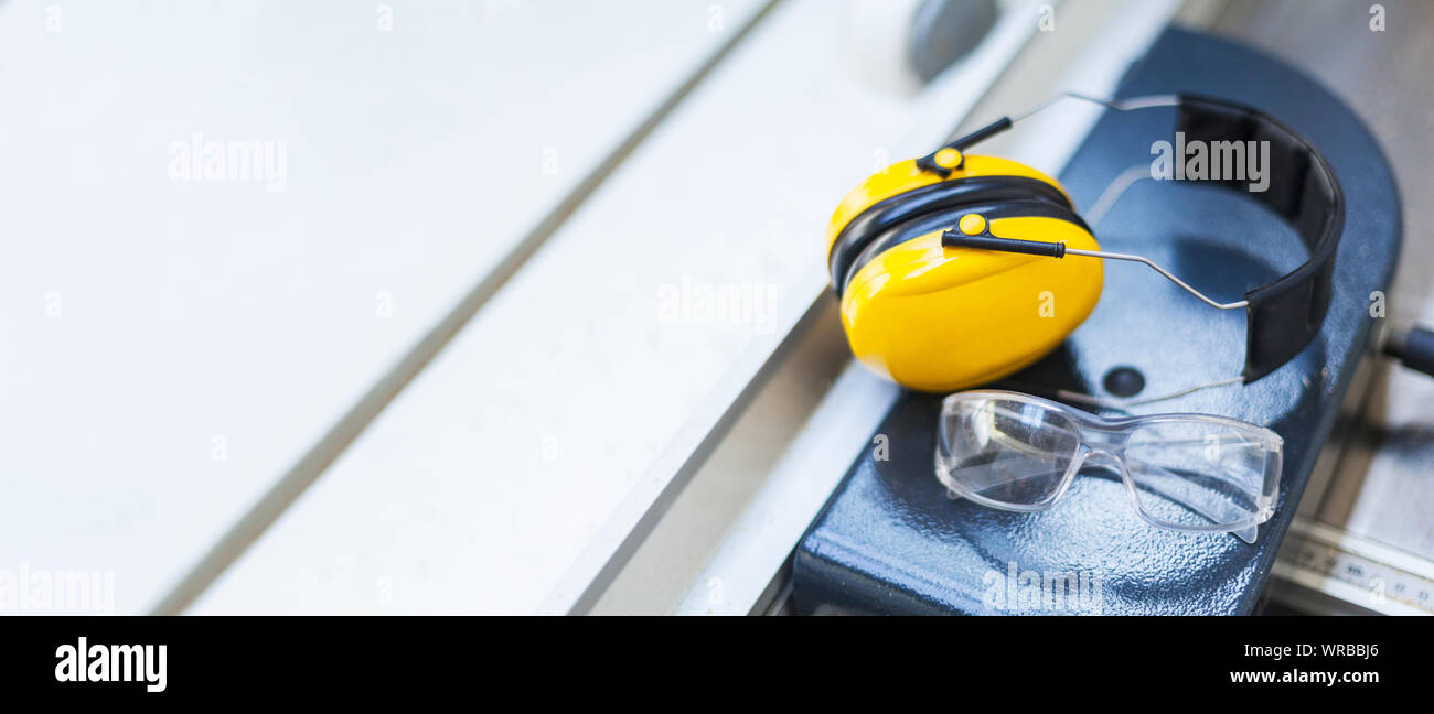 Gafas de protección de seguridad laboral y protección auditiva en sierra circular en el taller, volumen, protección ocular Foto de stock