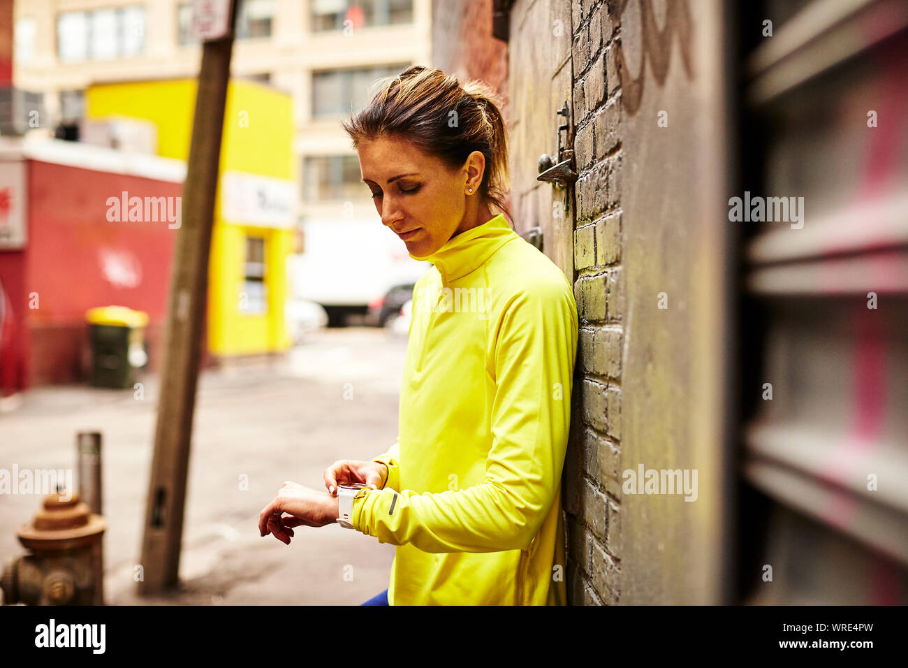 Una mujer colocando su reloj fitness en una calle de la ciudad. Foto de stock