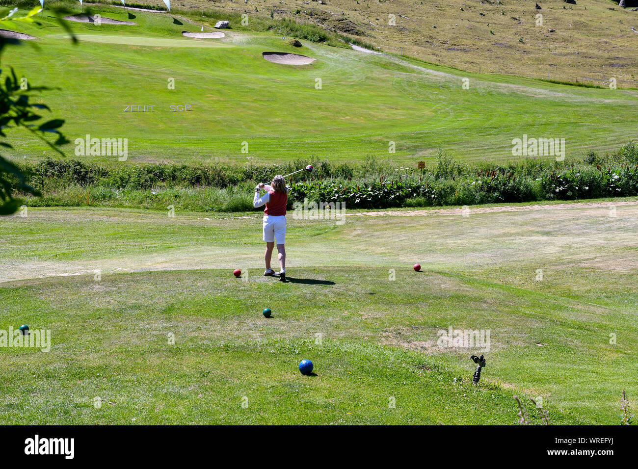 Una mujer de mediana edad jugando al golf en el Golf Club Courmayeur y Grandes Jorasses de Val Ferret, un valle al pie del macizo del Mont Blanc, Alpes, Italia Foto de stock