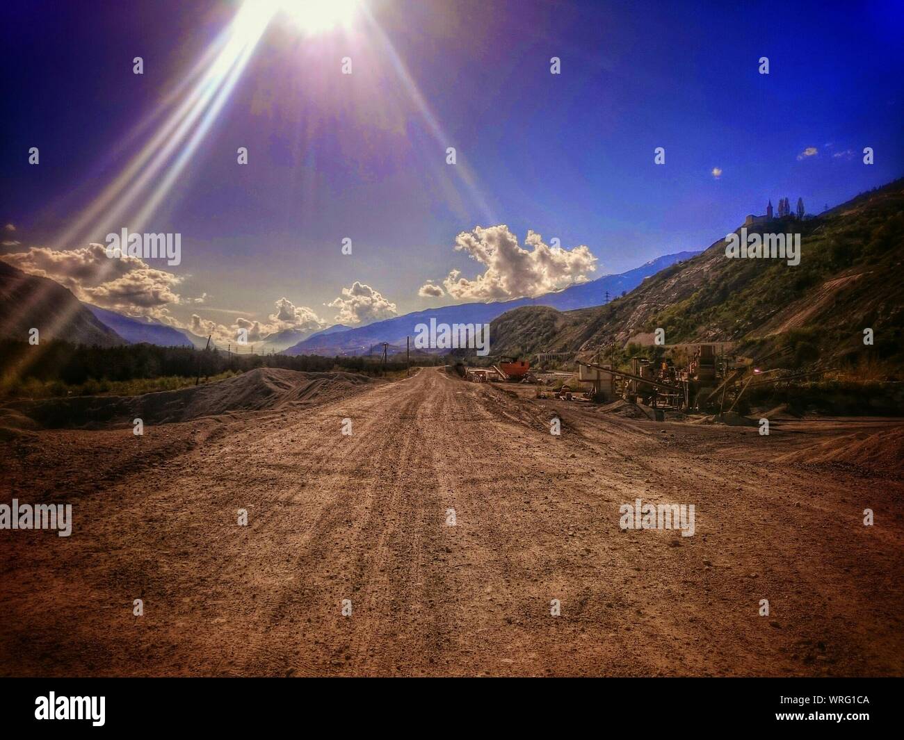 Vista de rayos de sol a través de camino de tierra en el paisaje de montaña Foto de stock