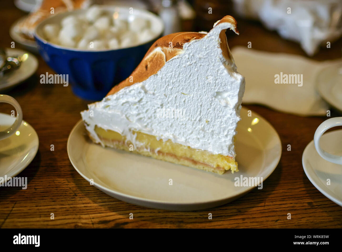 Gigantesco trozo de delicioso pastel de merengue de limón sobre la mesa de madera en un café. Foto de stock