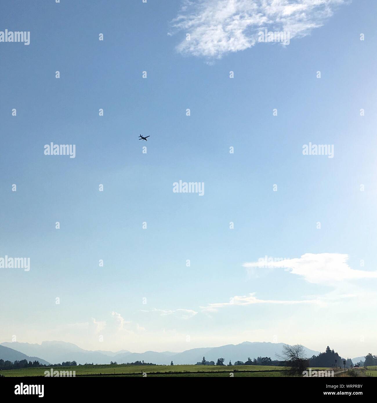 Vista lejana del avión volando sobre el campo contra el cielo Foto de stock