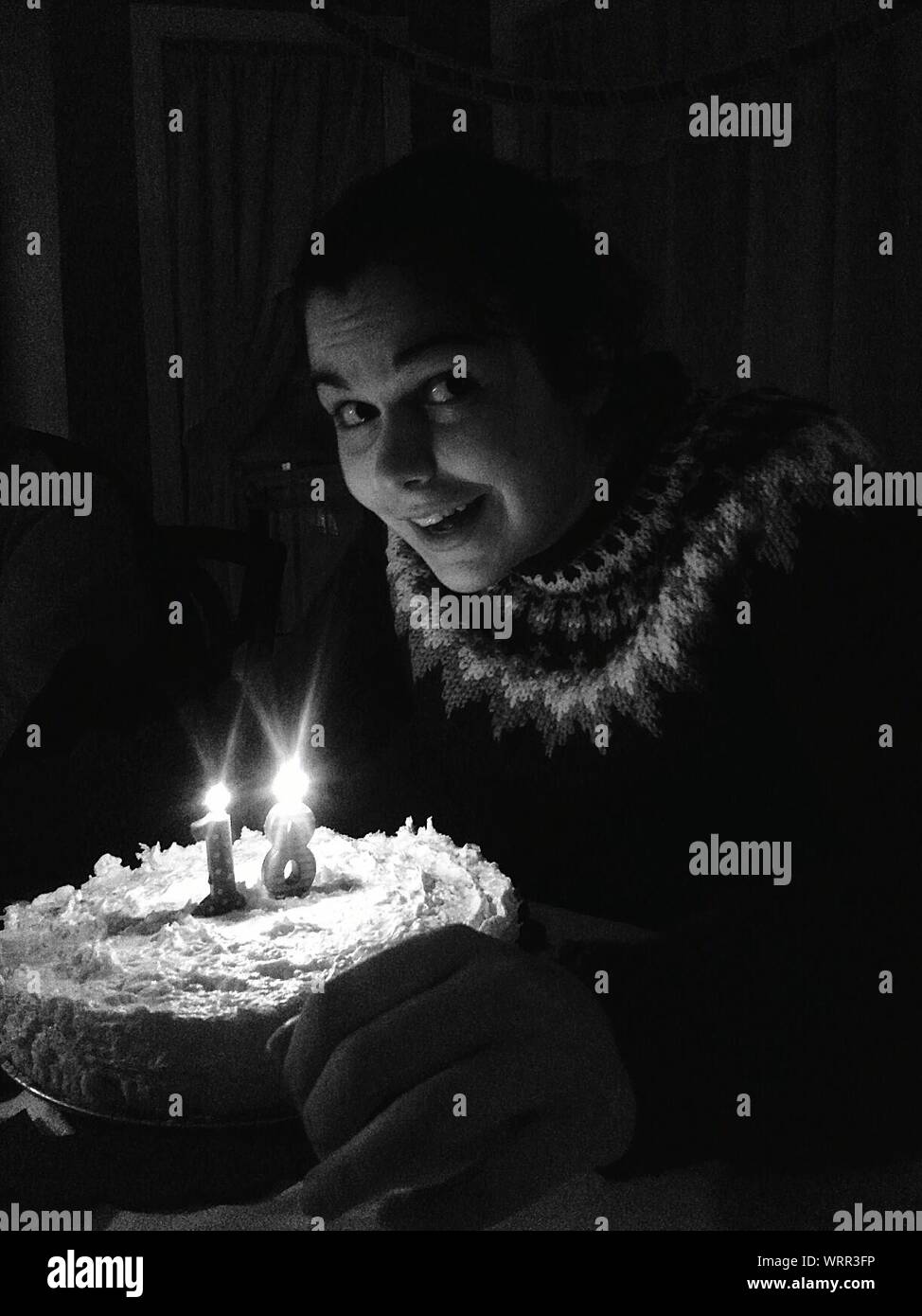Niña a la mesa con el pastel de cumpleaños mirando lateralmente Foto de stock