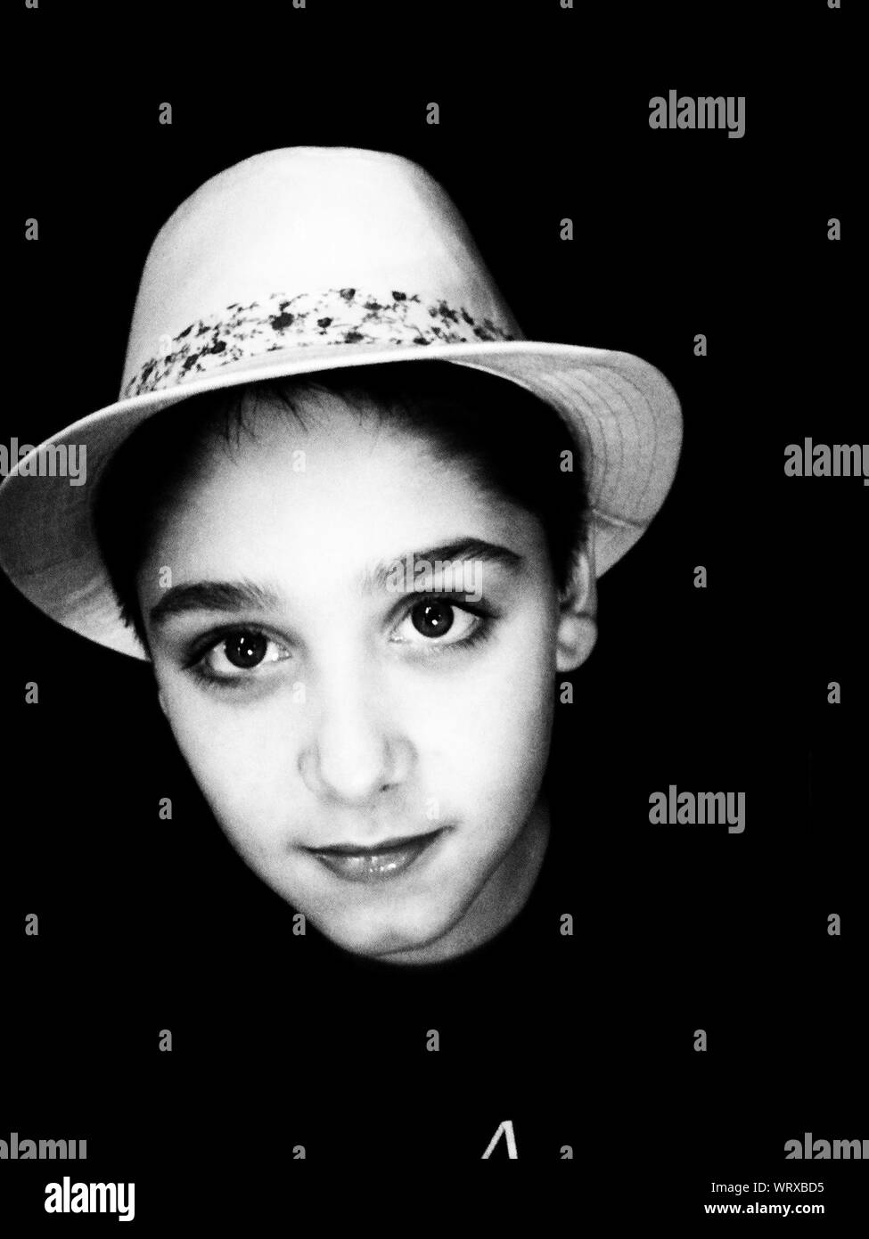 Close-up Retrato de niño usando Hat contra fondo negro Foto de stock