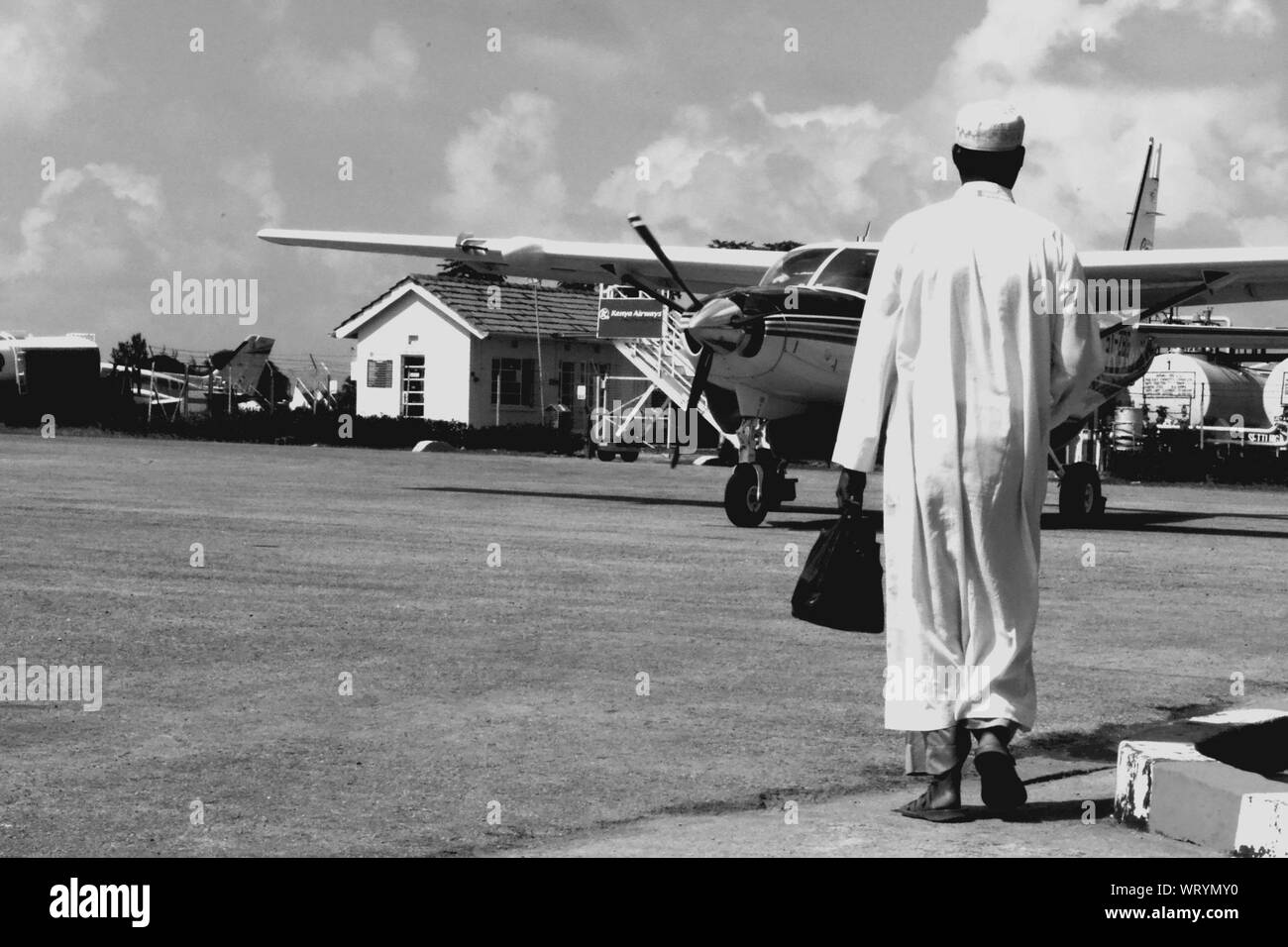 Hombre en ropa tradicional caminando hacia el avión privado Foto de stock