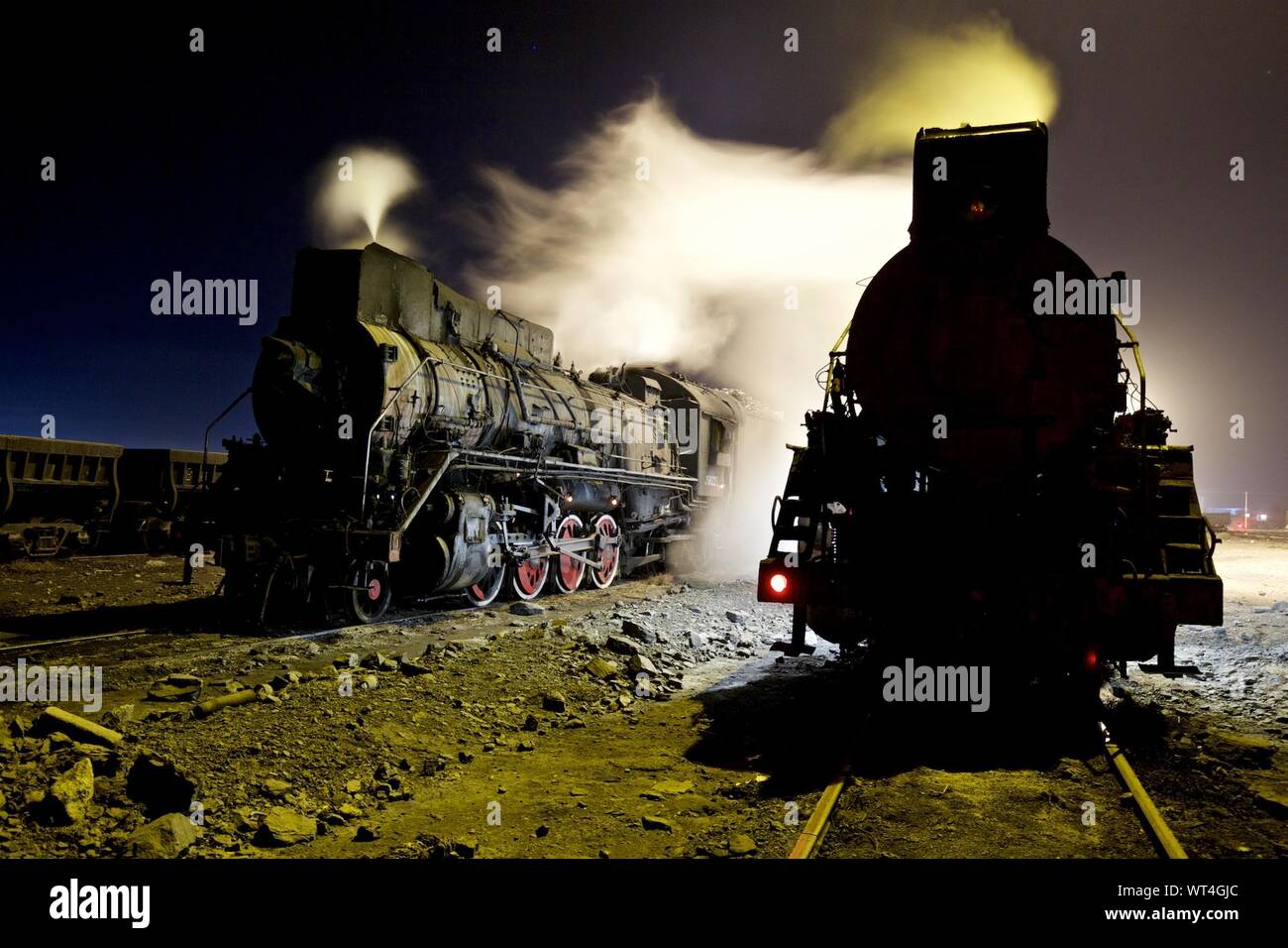 Los trenes a vapor que emite humo sobre las vías de ferrocarril en la noche contra el cielo Foto de stock