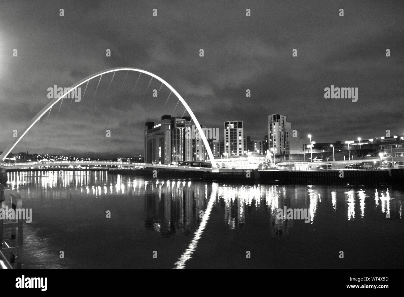 Puente Gateshead Millennium Bridge sobre el río Tyne por la ciudad iluminada por la noche Foto de stock