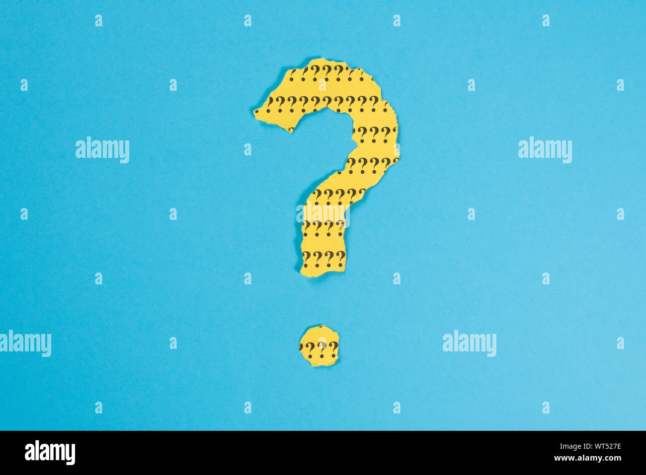 Símbolo de interrogación desde un teared papel amarillo sobre fondo azul. Concepto de FAQ, Preguntas y respuestas, preguntas y riddle Foto de stock