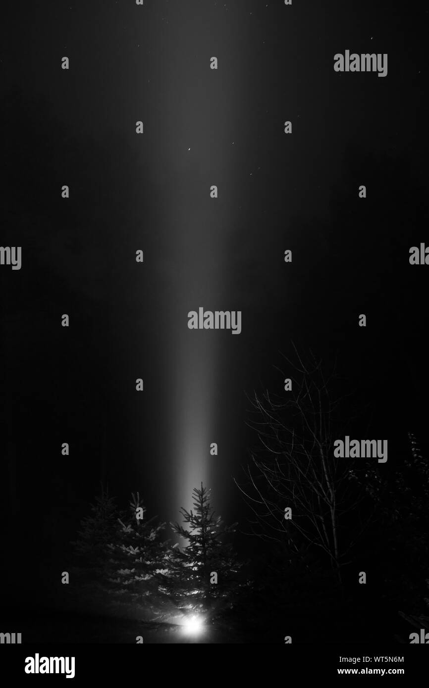 Haz de luz, disparando hacia el cielo en la noche neblinosa - blanco y negro Foto de stock